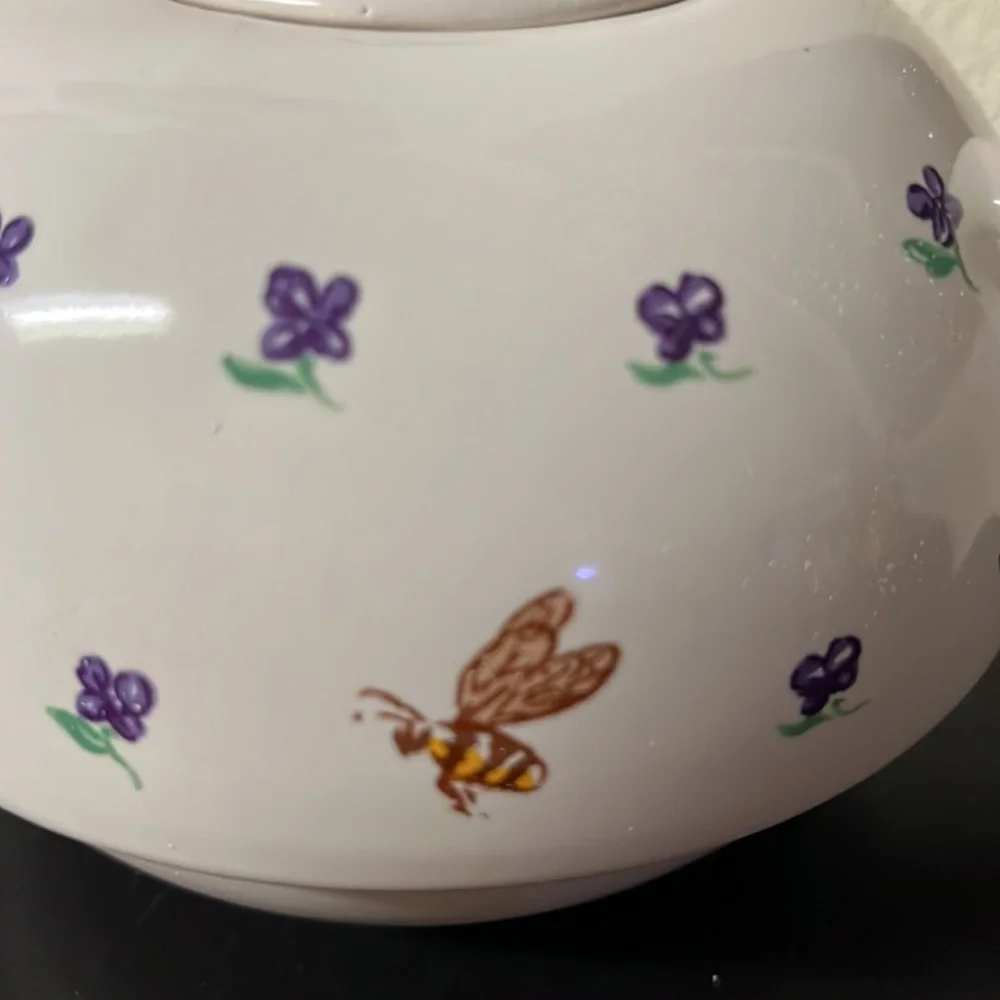 Small white teapot with violet and bee details.